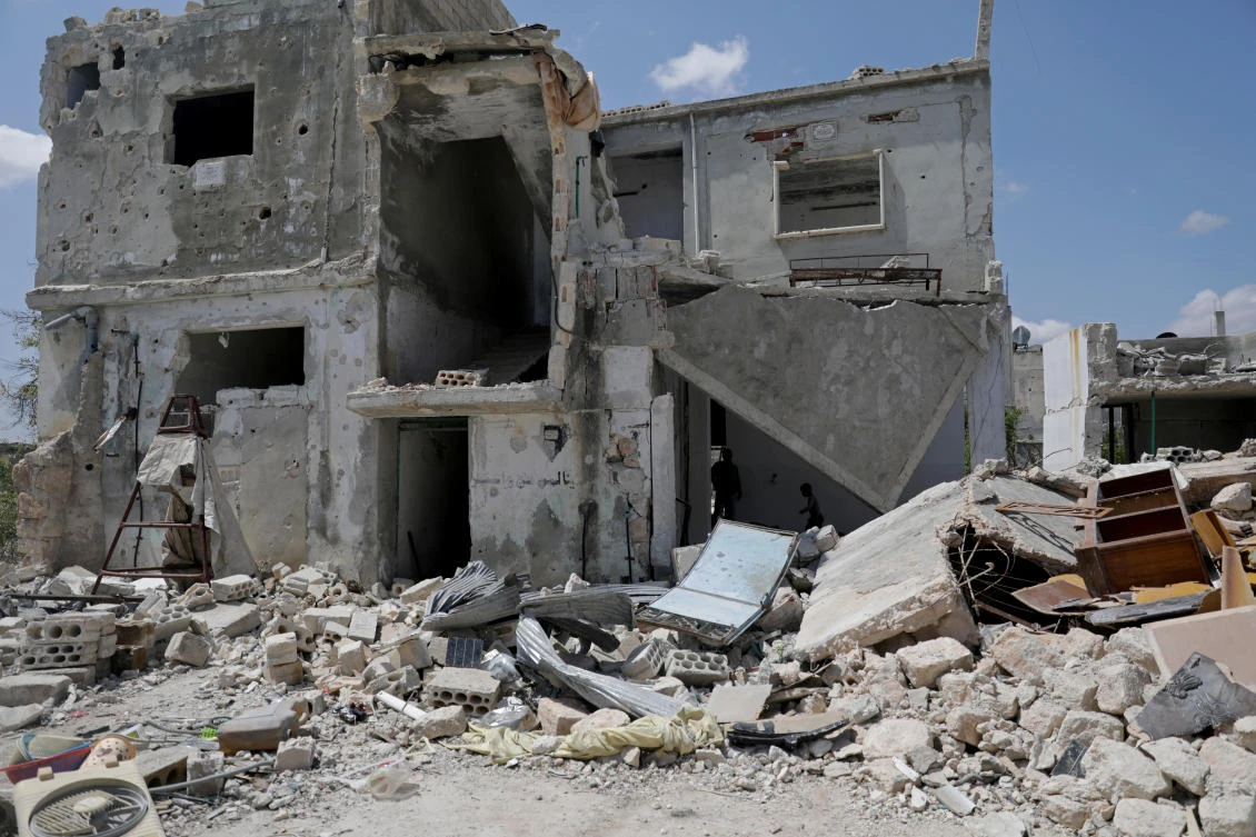 Saher al-Ali's family members stand inside their damaged house in the rebel-held town of Nairab, Idlib region, Syria April 17, 2020. Picture taken April 17, 2020. (Reuters)