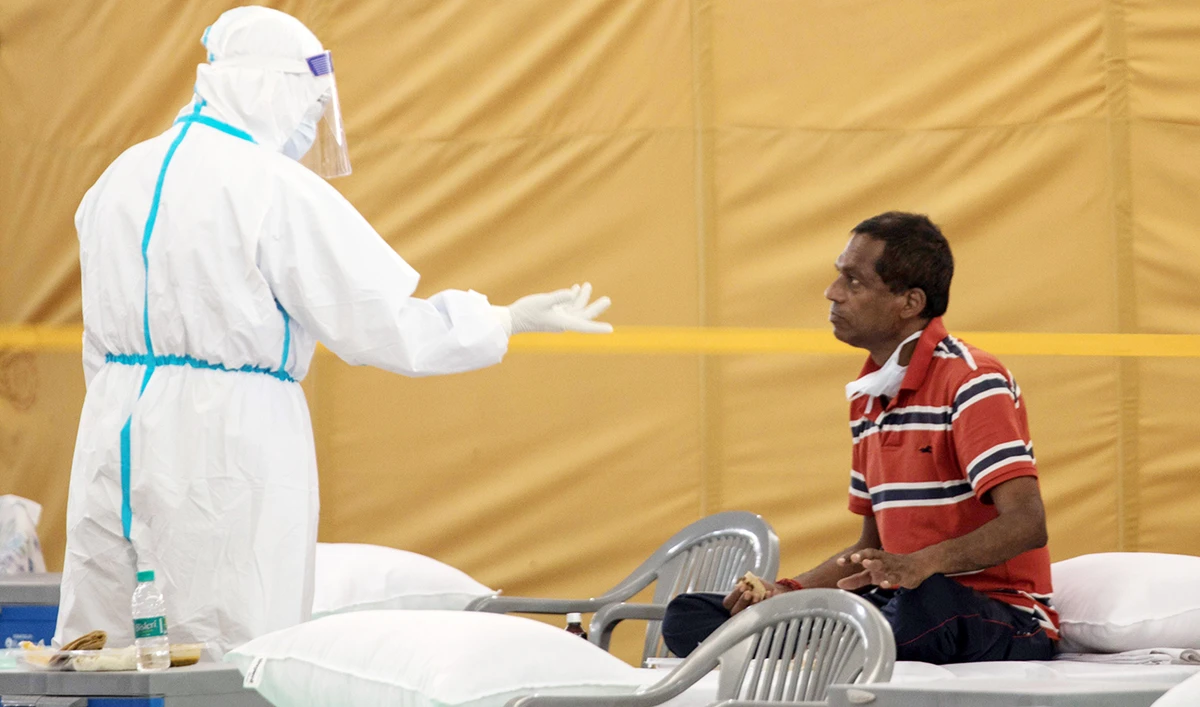 A health official wearing personal protective equipment attends to a patient inside the campus hall of Radha Soami Satsang Beas, converted into a coronavirus care center in New Delhi on Monday. (AFP)