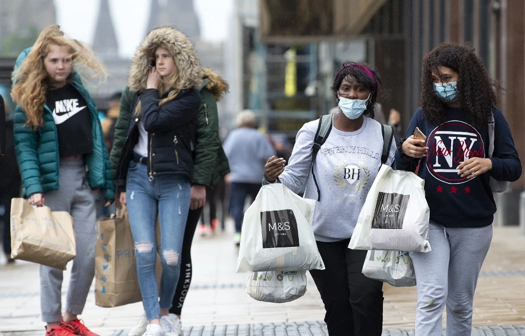 Shoppers, some wearing PPE (personal protective equipment), of a face mask or covering as a precautionary measure against spreading COVID-19, carry their purchases in shopping bags in Edinburgh on June 29, 2020. (File/AFP)