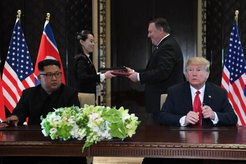 Donald Trump and Kim Jong Un look on as documents are exchanged between US Secretary of State Mike Pompeo and the North Korean leader’s sister Kim Yo Jong during their historic in Singapore on June 12, 2018. (AFP)