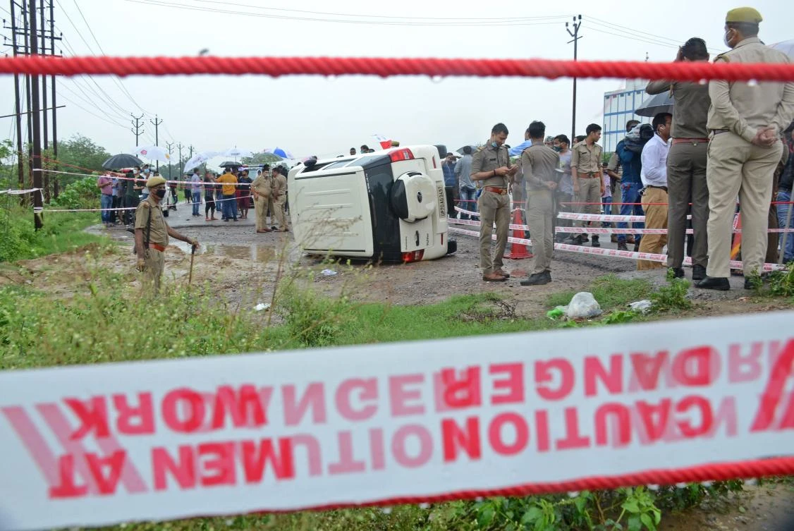 Policemen stand guard next to an overturned vehicle after the gangster Vikas Dubey was shot dead by police, on a highway at Sachendi in Uttar Pradesh state on July 10, 2020. (AFP)