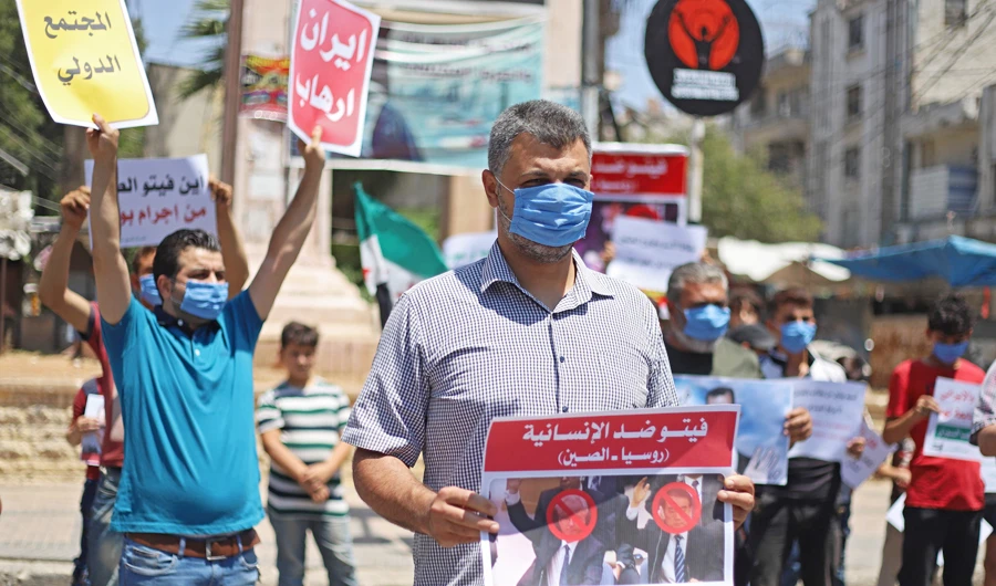Syrian protesters in Idlib carry placards expressing their opposition to Russia’s attempt to reduce cross-border aid to millions in the northwest of the country. (AFP)
