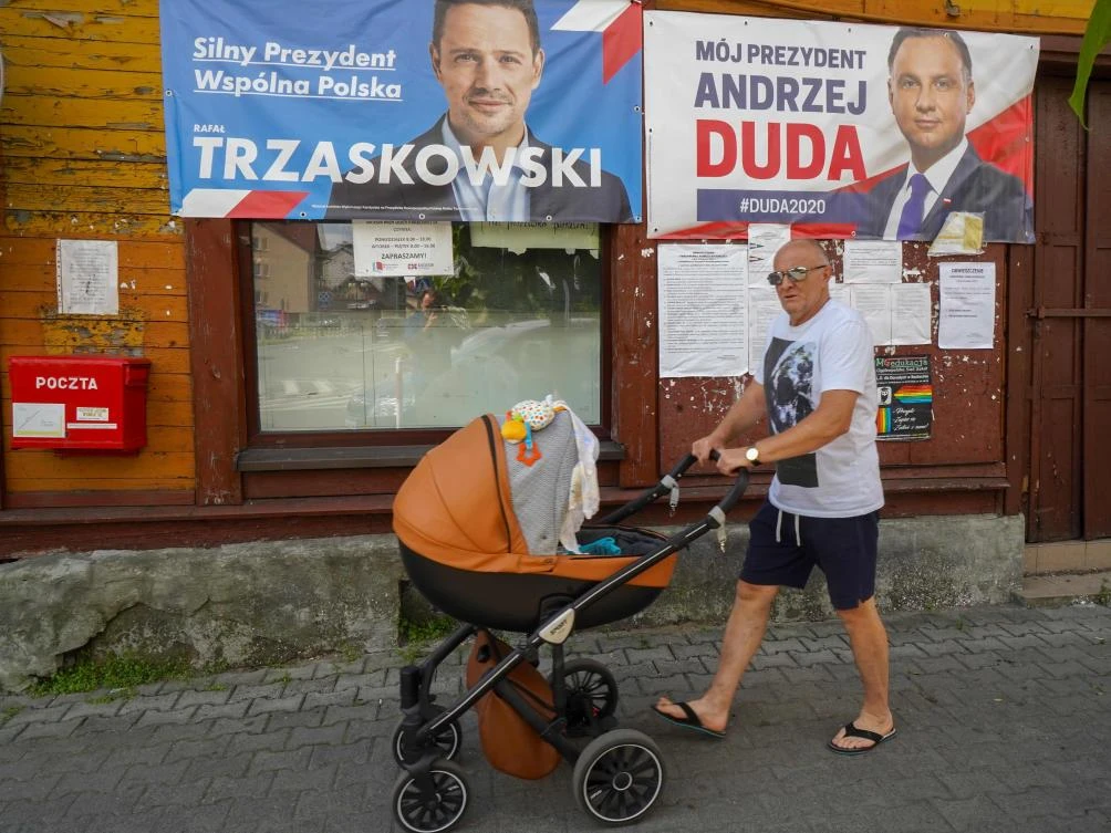 A man pushes a pram past campaign posters of Warsaw Mayor and candidate in Poland's presidential election, Rafal Trzaskowski (L) and of President Andrzej Duda (R) on July 9, 2020 in Raciaz, Poland, ahead of the July 12, 2020 presidential election. (AFP)