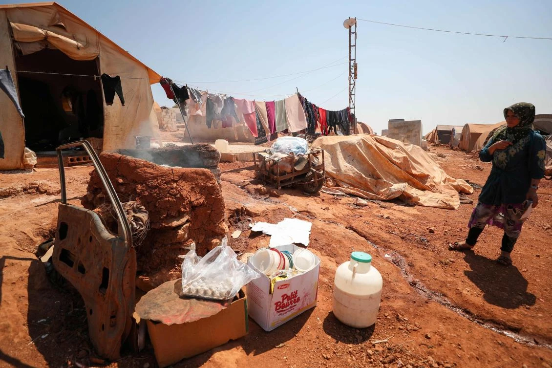 A displaced Syrian woman, stands next to her tent at a camp for displaced Syrians from Idlib and Aleppo provinces, near the town of Maaret Misrin in Idlib province on July 11, 2020. (AFP)