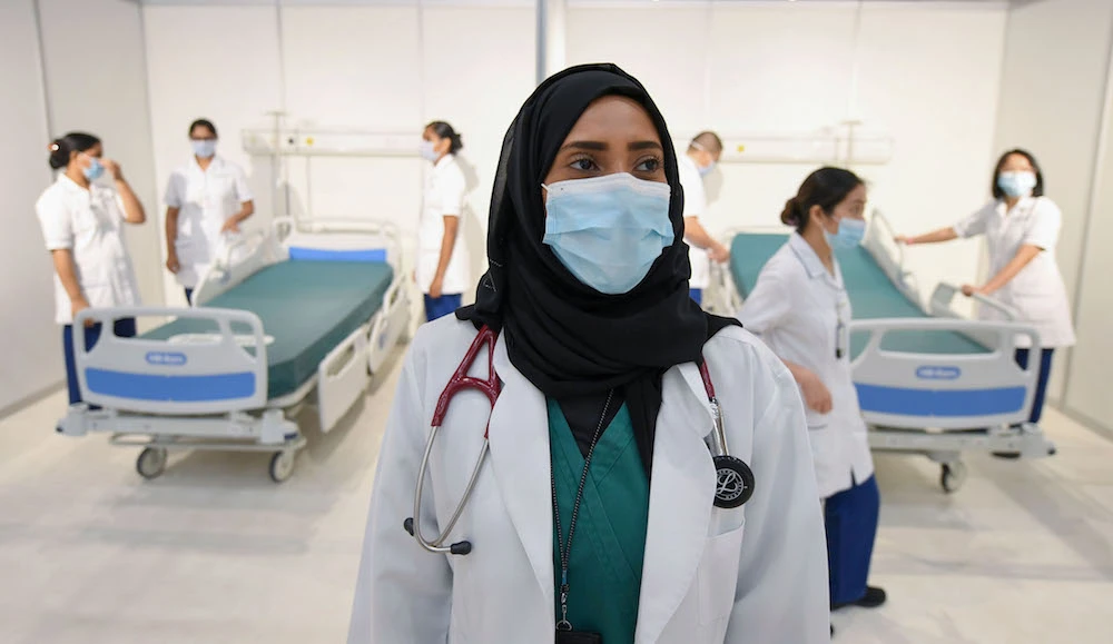 An Emirati doctor looks on as nursing staff prepare beds in a huge field hospital being built by the government of Dubai in the United Arab Emirates, on April 14, 2020. (AFP)