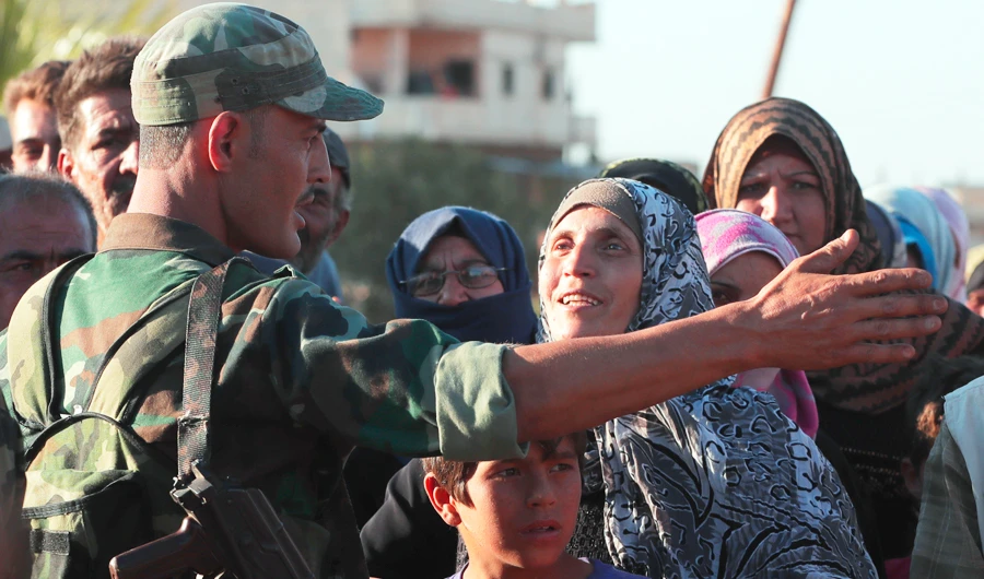 A woman talks with a soldier of the Syrian army during distribution of humanitarian aid from the Russian military, in the town of Rastan, Syria. (AP)