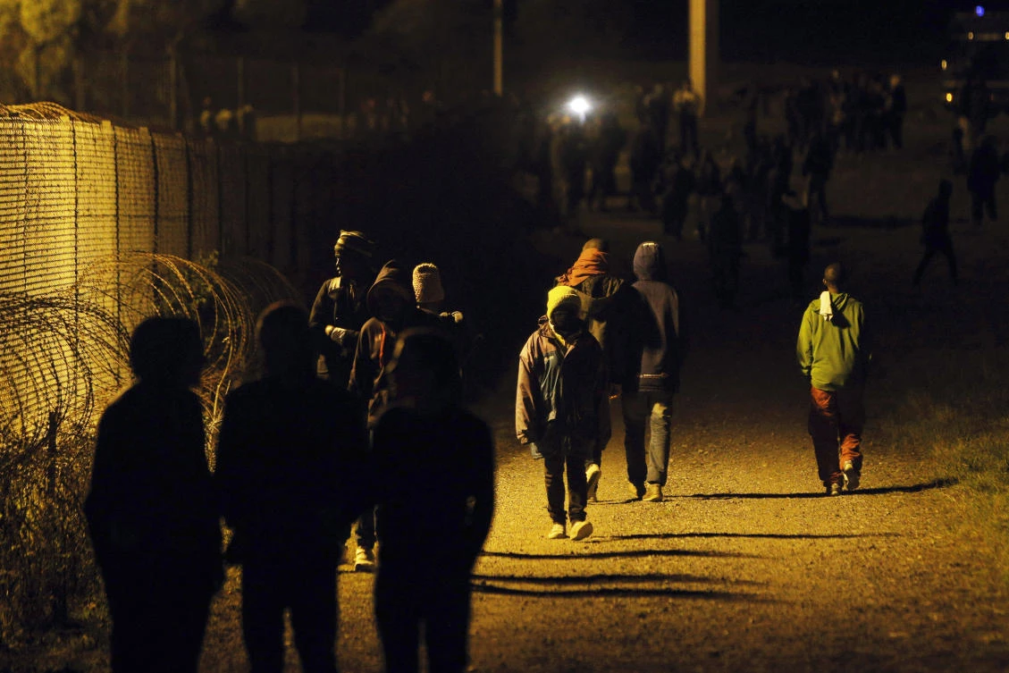 Migrants walk along a fence outside the Eurotunnel area, in Calais, northern France, in a Wednesday, July 29, 2015 file photo. (AP)