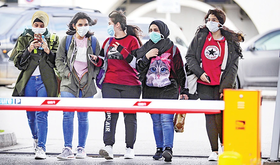 Lebanese women wearing protective masks walk outside Beirut’s Rafik Hariri University Hospital as cases of coronavirus soars on Sunday. (AFP/File)