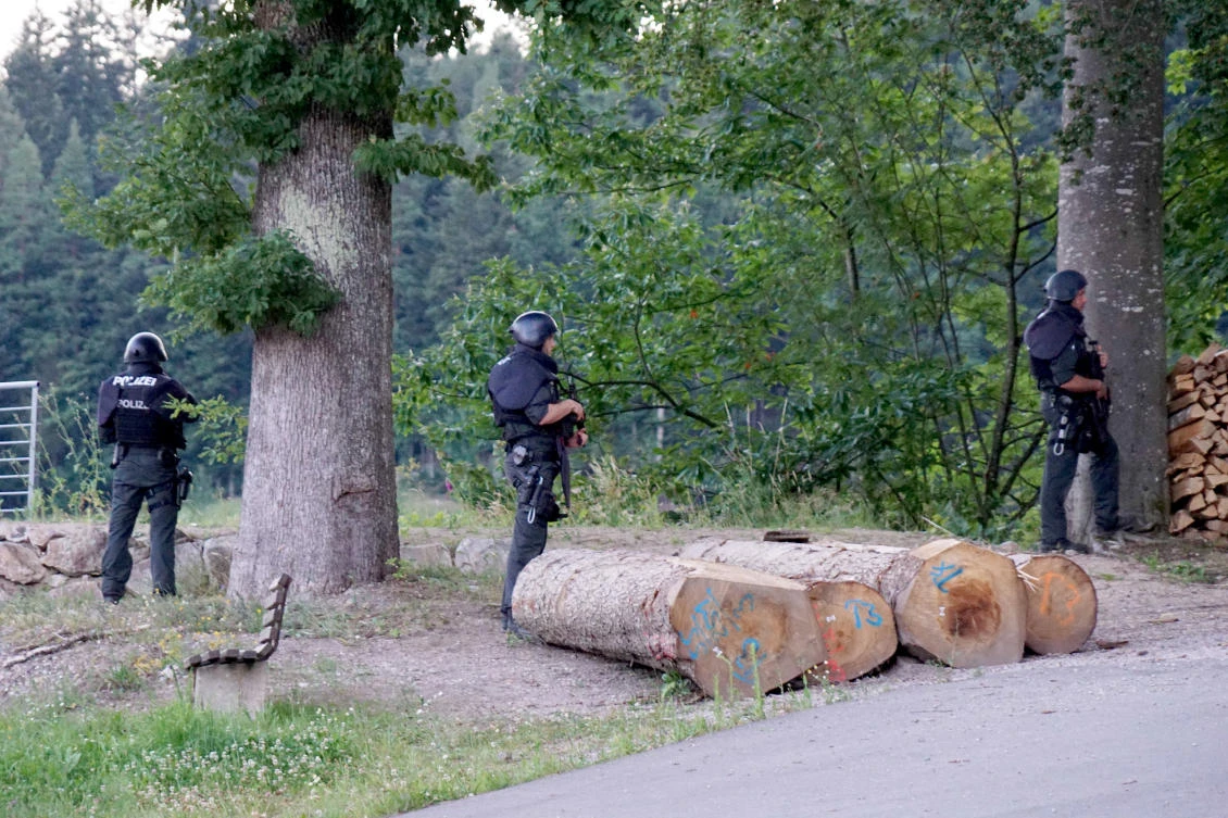Police officers stay outside a wooded area during a manhunt near Oppenau, Germany on Monday, July 13, 2020. (dpa via AP)