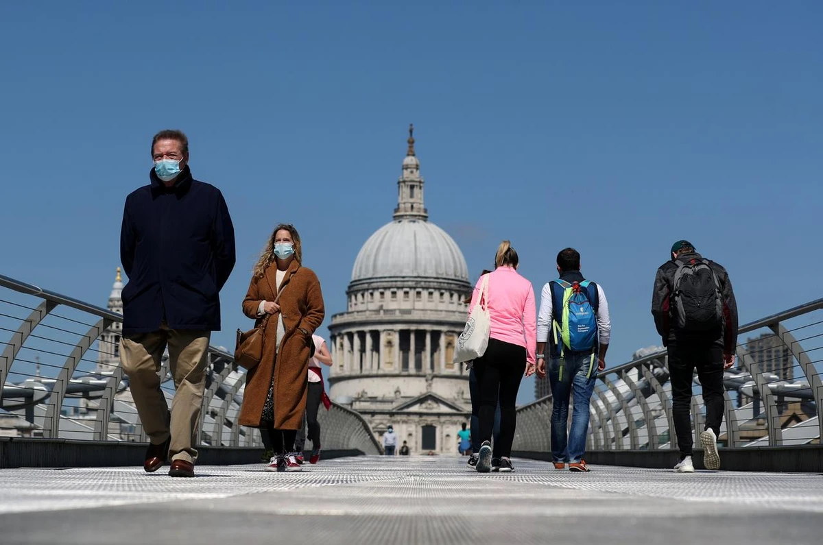 People wearing face masks cross Millennium Bridge, as the spread of the coronavirus disease (COVID-19) continues, in London, Britain, April 25, 2020. (Reuters)
