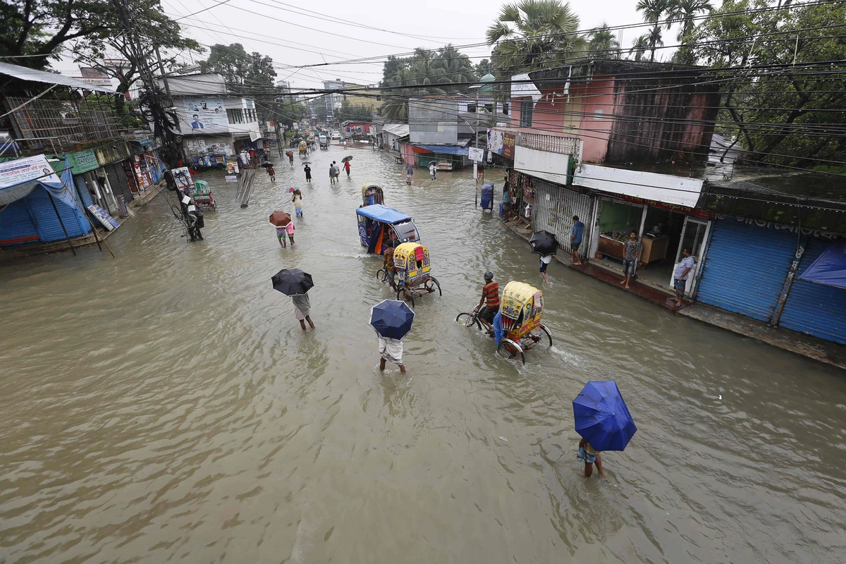 In this photograph taken on July 12, 2020, people make their way through flood waters in Sunamgong. (AFP)