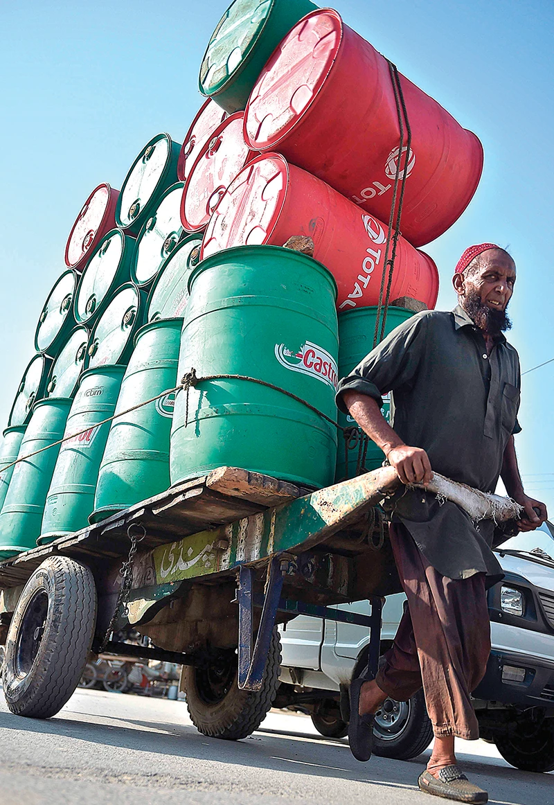 An Indian laborer pulls a cart laden with empty oil drums. OPEC and its allies led by Russia have cut output by 10 million bpd since May. (AFP)