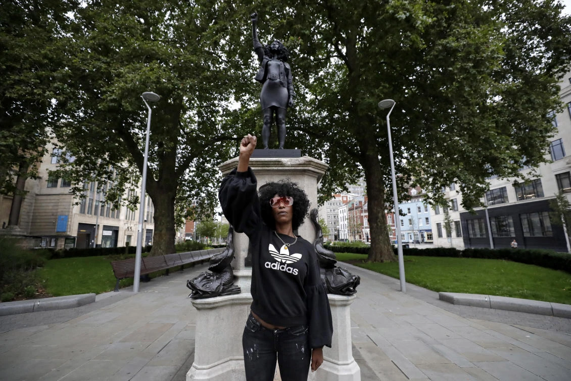 Jen Reid poses for photographs in front of the new black resin and steel statue portraying her. (AP)