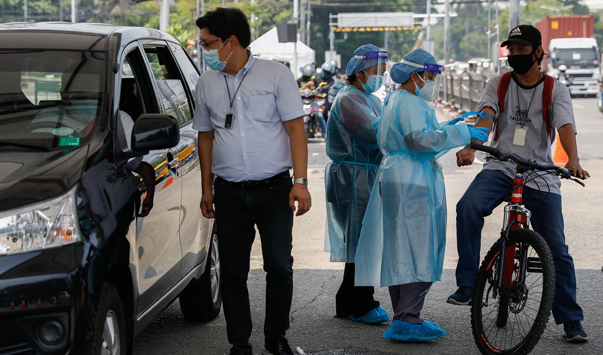 Healthcare workers take blood samples from a bike rider at a coronavirus disease (COVID-19) drive-thru testing center in Manila, Philippines, July 15, 2020. (Reuters)