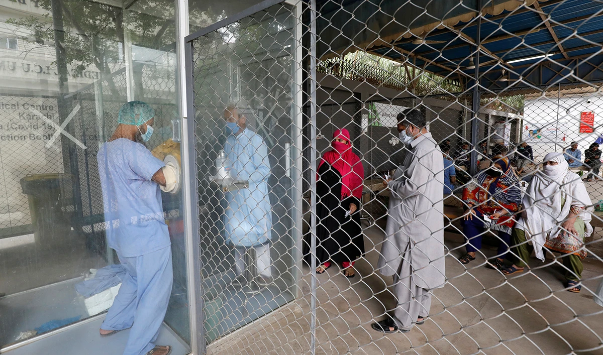 A paramedic takes nasal swab samples from the glass booth as people waiting to be tested for the coronavirus disease (COVID-19), in Karachi, Pakistan July 15, 2020. (Reuters)