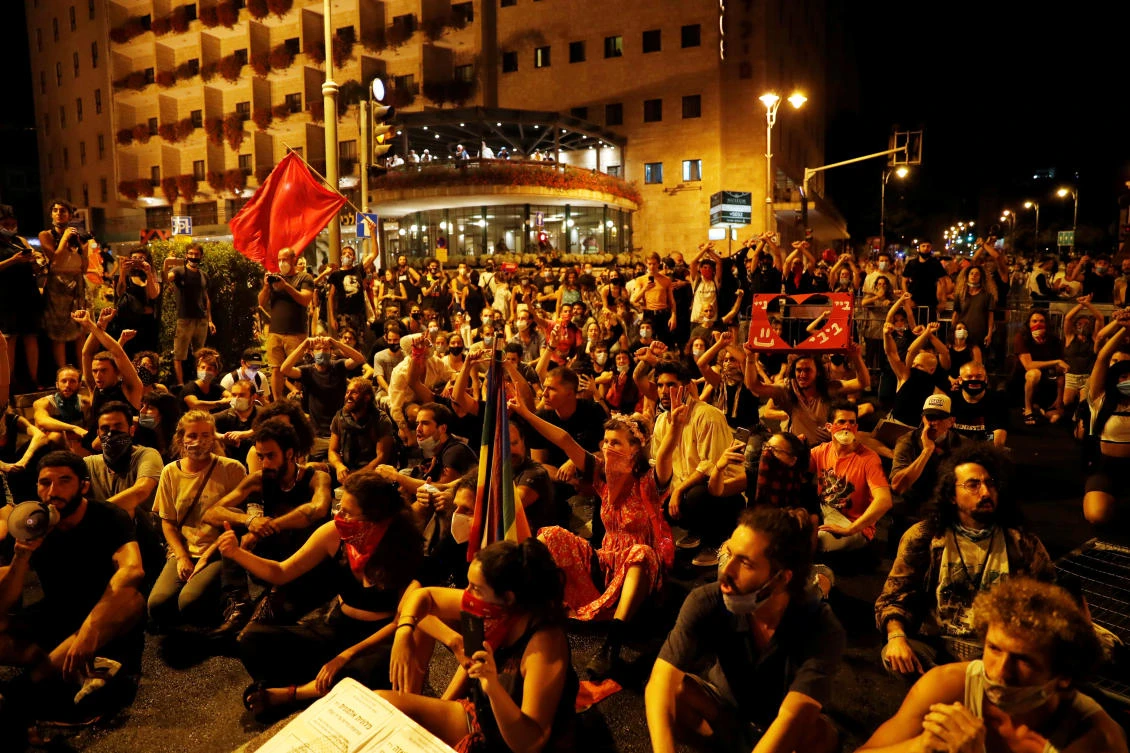 Residents sit on a road as they protest against Israeli Prime Minister Benjamin Netanyahu and his government’s response to the financial fallout of the coronavirus disease crisis on July 15, 2020. (Reuters)