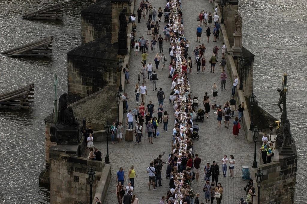 People walk past and sit at a half-kilometre long table set up on the Charles Bridge in Prague to celebrate the end of the restrictions linked to the new coronavirus pandemic on June 30, 2020. (File/AFP)