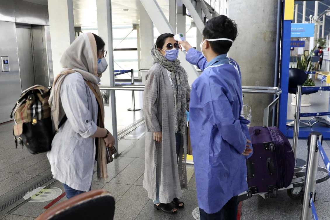 A health worker checks the temperature of passengers upon arrival at the departure terminal of Tehran's Imam Khomeini airport, Iran. (File/AP)