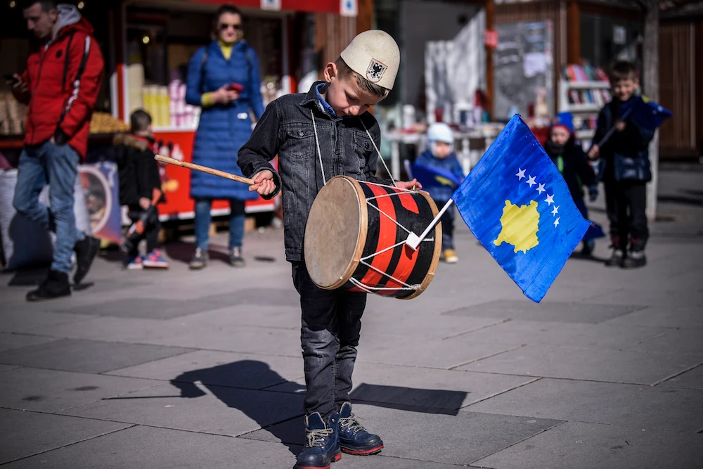 A Kosovo Albanian boy with a traditional hat plays drum in downtown Pristina on February 17, 2020, on the day of 12th anniversary of Kosovo's declaration of independence. (AFP/File Photo)