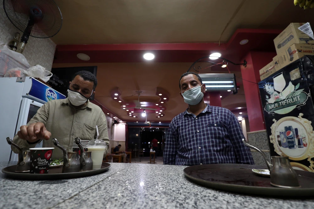 Waiters wait for an order at a cafe in the Egyptian capital Cairo, after authorities relaxed the lockdown measures in place to curb the spread of coronavirus. (File/AFP)