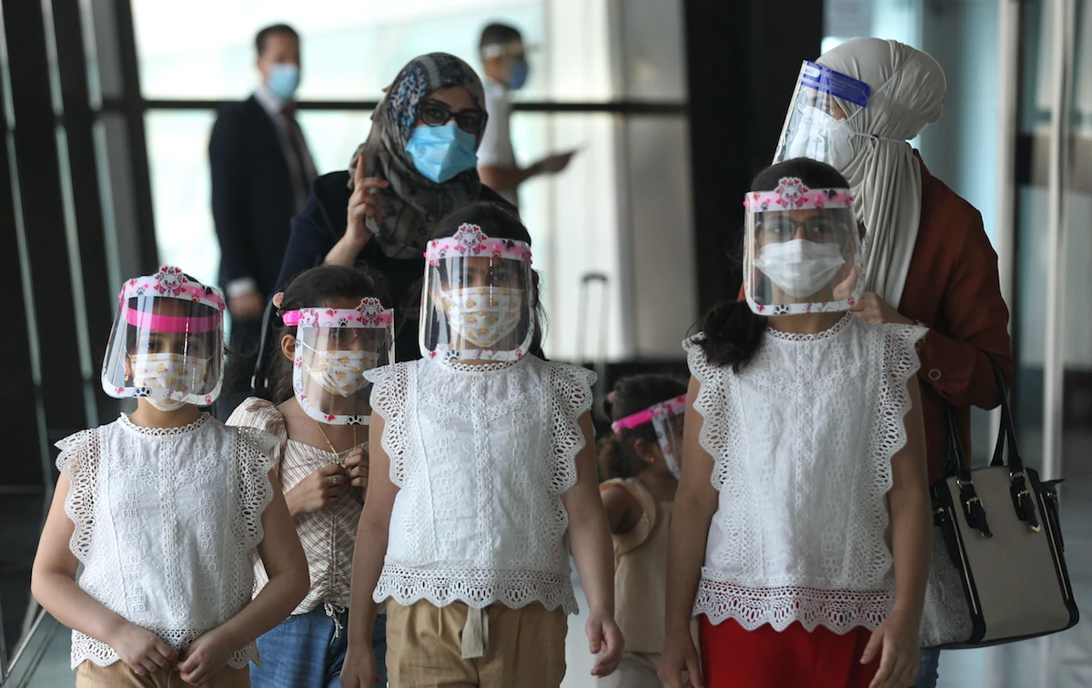 An Iraqi family wearing protective masks walk at the departure hall of Baghdad international airport following its reopening on July 23, 2020. (AFP)