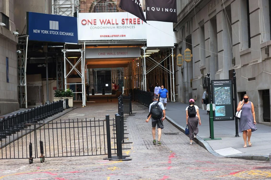 People walk along Wall Street near the New York Stock Exchange (NYSE) on July 23, 2020 in New York City. (AFP)