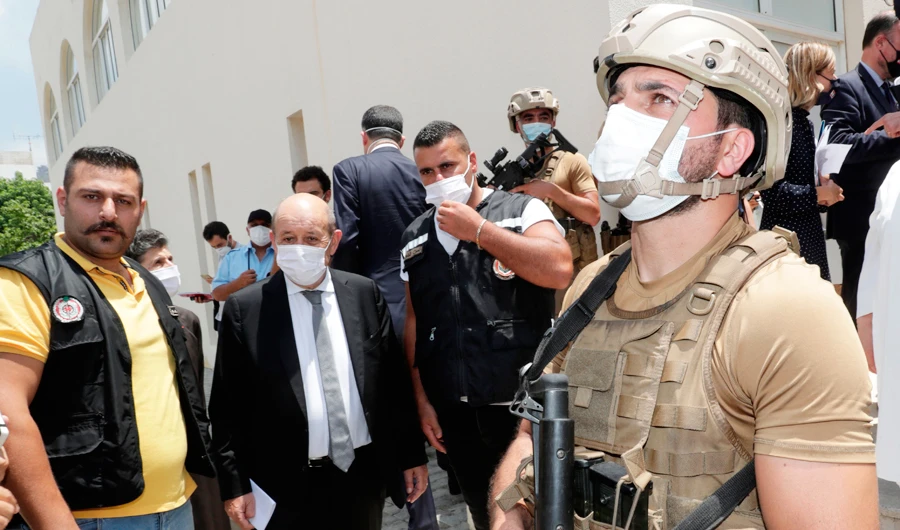 Security officers accompany French Foreign Minister Jean-Yves Le Drian as he leaves the Carmel Saint Joseph School in Mechref, southeast of Beirut. (AFP)