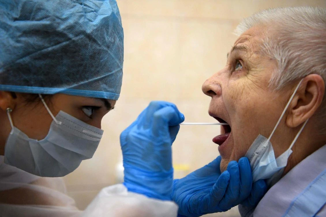 A medical person wearing protective equipment takes a swab from a woman at a medical facility in Moscow on July 16, 2020, on the first day the Russian capital started providing free testing for the coronavirus disease to its residents. (AFP)