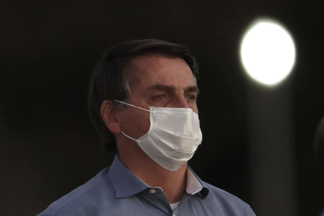 Brazil’s President Jair Bolsonaro, who is infected with COVID-19, wears a protective face mask as he attends a Brazilian flag retreat ceremony outside his official residence the Alvorada Palace, in Brasilia, Brazil. (File/AP/Eraldo Peres)