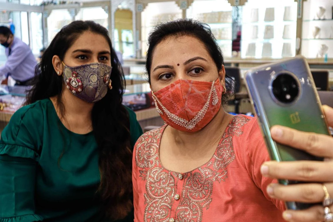 Customers wearing handmade facemasks studded with diamonds take selfie pictures at D Khushalbhai Jewellers showroom in Surat, some 270 km from Ahmedabad on July 25, 2020. (AFP)