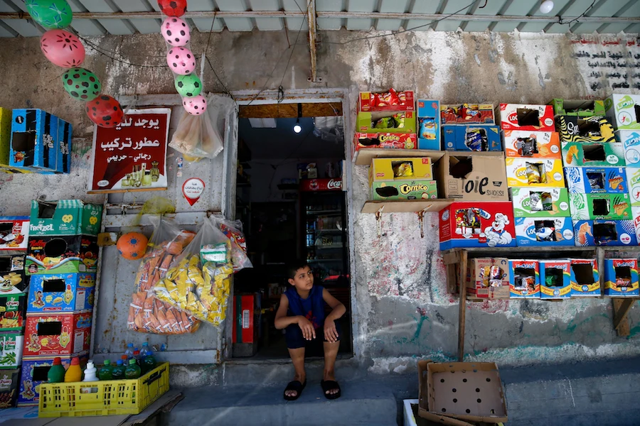 A young Palestinian sits at the entrance of a shop in Gaza City on June 3, 2020, amid the novel coronavirus pandemic crisis. (AFP)