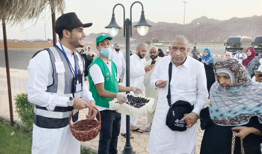 Sultan Al-Harbi, left, welcomes pilgrims with Oud and dates at one of the checkpoints in Madinah. (Photos/Supplied)