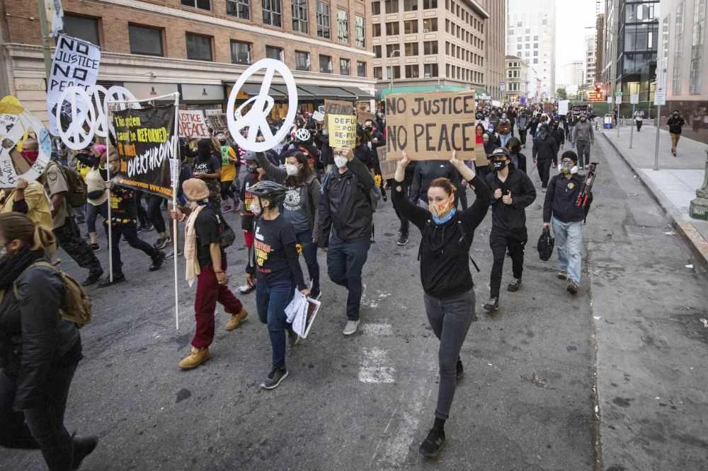 Black Lives Matter protesters march through downtown Oakland on July 25, 2020, in Oakland, California. Some of them later set fire to a courthouse, damaged a police station and assaulted officers after a peaceful demonstration intensified late Saturday, Oakland police said. (AP Photo/ Christian Monterrosa)