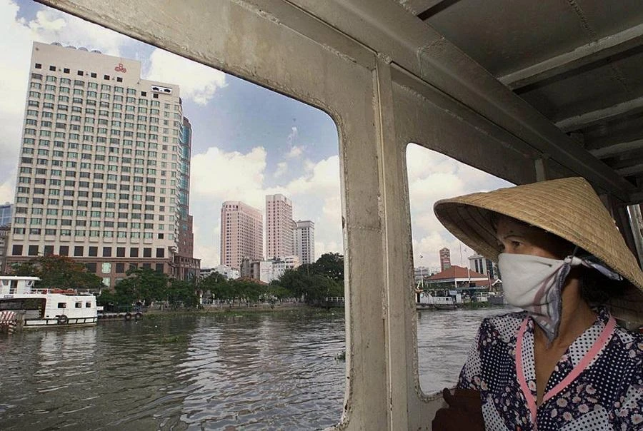 A woman peers from a ferry crossing Saigon River toward the center of Ho Chi Minh City, formerly known as Saigon, 24 April 2000. (File/AFP)