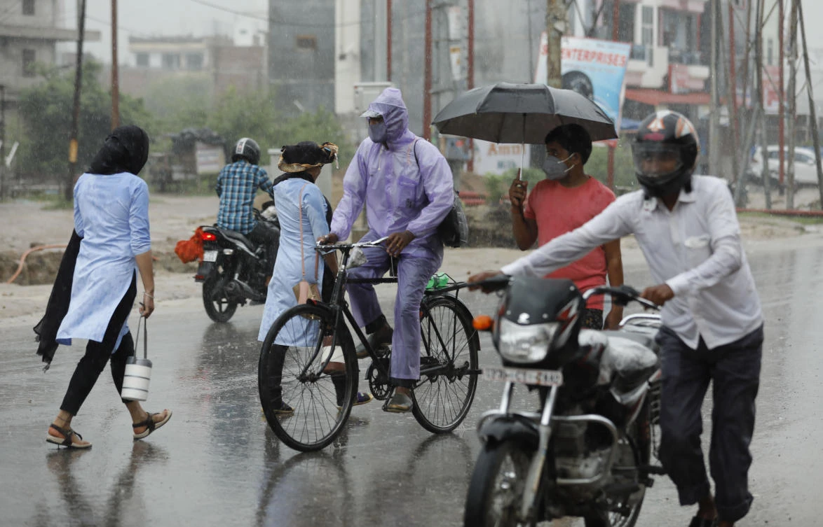 People wear face masks and move through a street in the rain in Prayagraj, India, Wednesday, July 29, 2020. India is the third hardest-hit country by the pandemic in the world after the United States and Brazil. (AP)