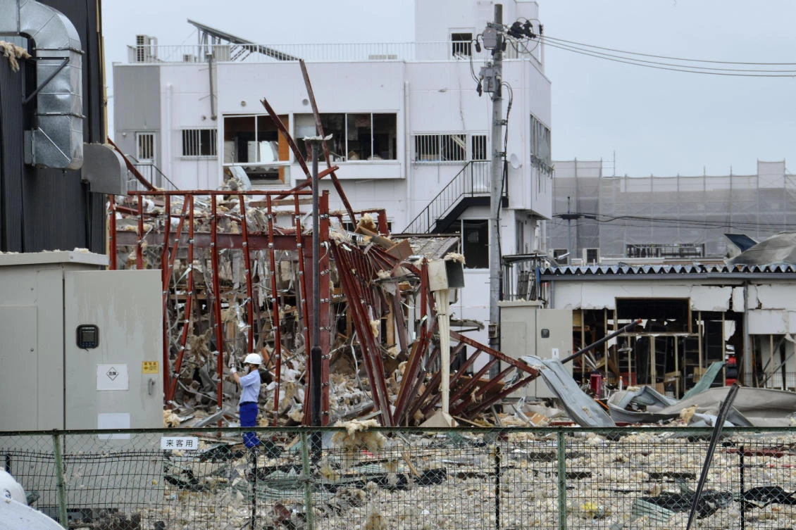 An investigator stands in front of a damaged building following an explosion in Koriyama, Fukushima prefecture, northern Japan on Thursday. (Kyodo News via AP)