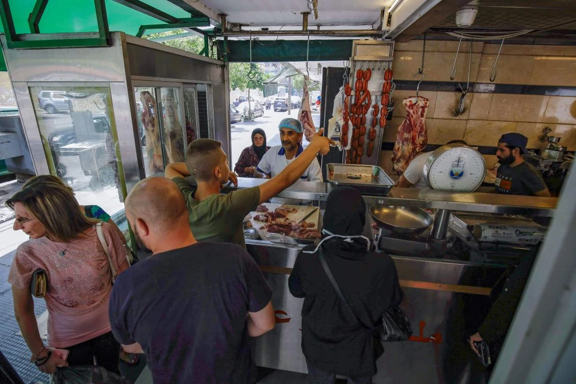 People wait for their orders at a butcher shop in Lebanon’s northern port city of Tripoli, as Muslims across the world get ready to celebrate Eid Al-Adha, July 28, 2020. (AFP)