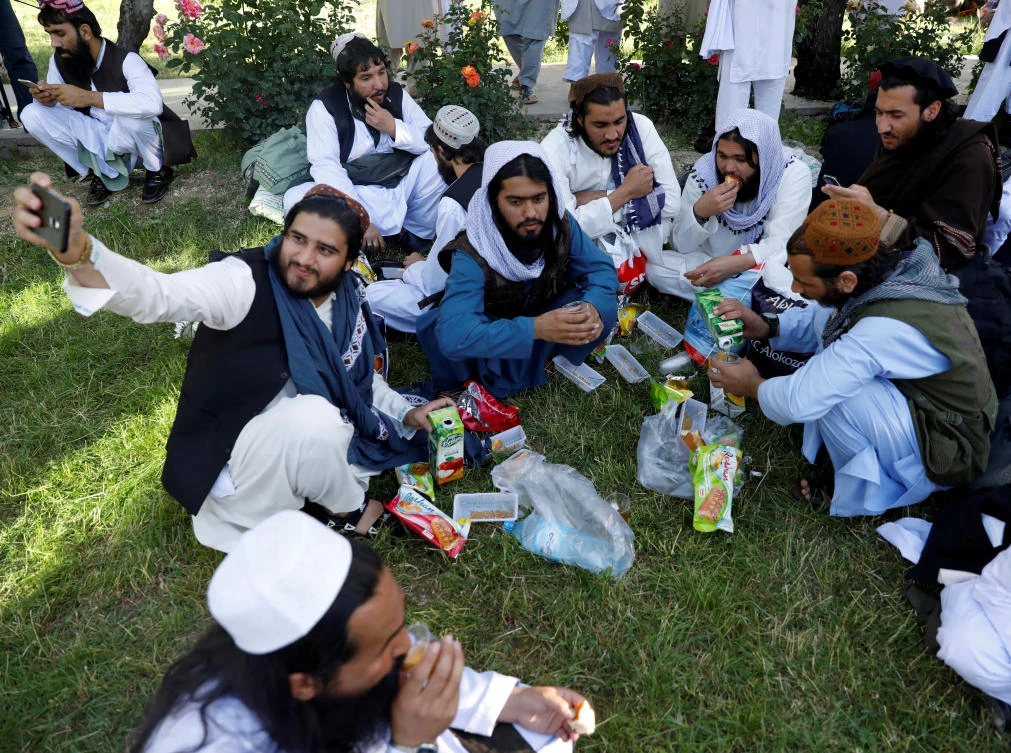 A newly freed Taliban prisoner takes a selfie as others have juice and biscuits at Pul-i-Charkhi prison, in Kabul, Afghanistan, May 26, 2020. (Reuters)