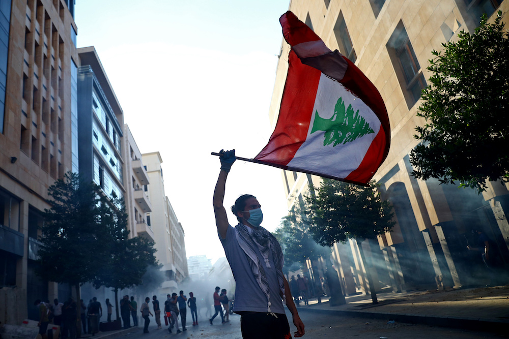 A demonstrator waves a Lebanese flag during anti-government protests that have been ignited by a massive explosion in Beirut, Lebanon August 10, 2020. (Reuters)