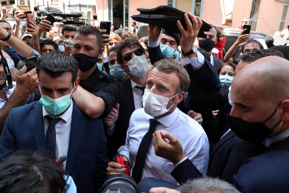 French President Emmanuel Macron, center, wears a mask to help prevent the spread of the coronavirus, as he visits the Gemayzeh neighborhood, which suffered extensive damage from an explosion on Tuesday that hit the seaport of Beirut, Lebanon, Thursday, Aug. 6, 2020. (AP)