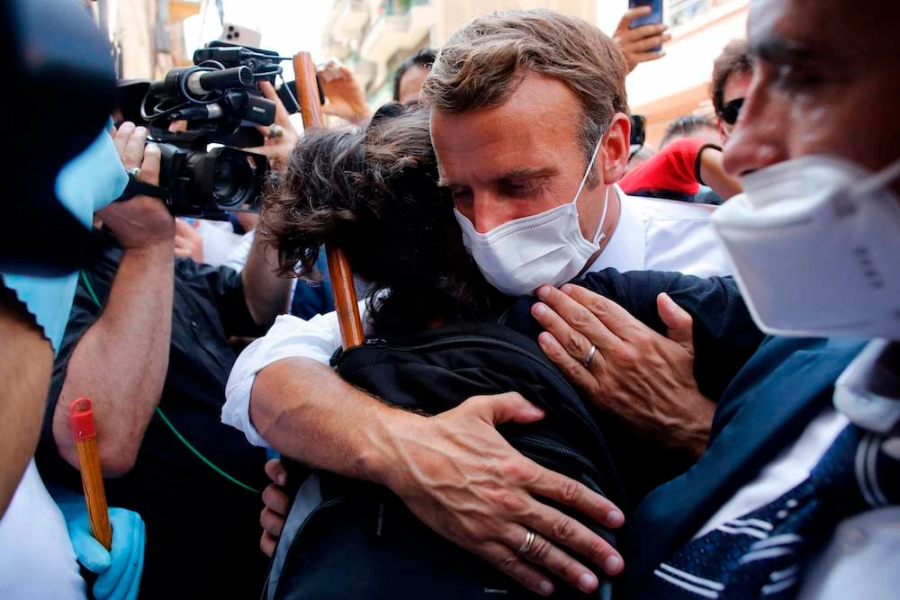 French President Emmanuel Macron hugs a resident as he visits a devastated street of Beirut, Lebanon, on August 6, 2020 after the massive explosion ripped through the city. (AFP)