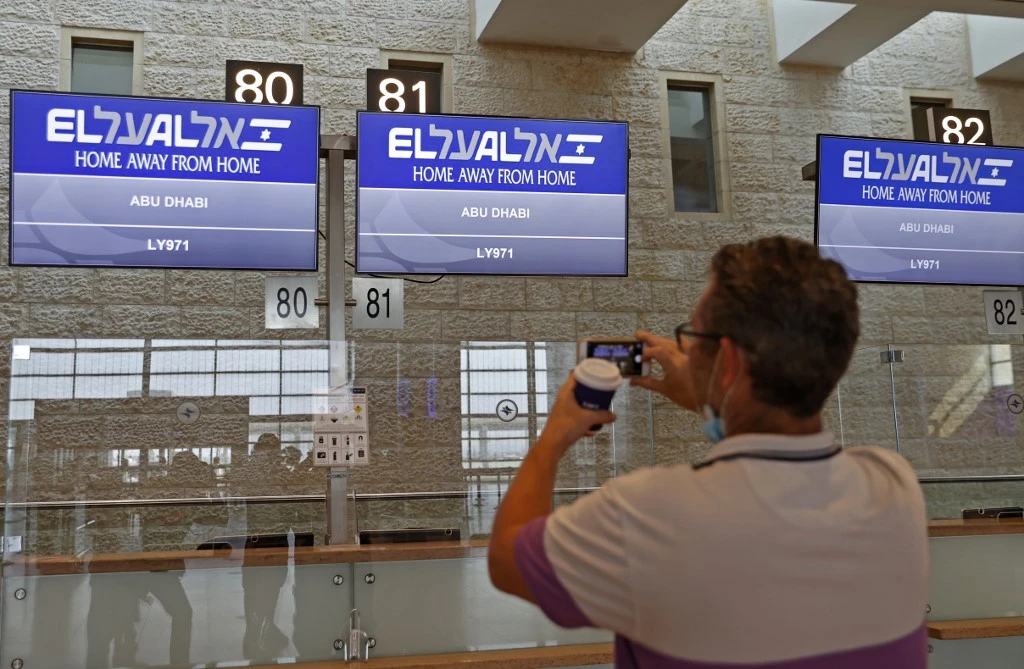 A passenger takes a picture of screens displaying the flight number of the first-ever commercial flight from Israel to the UAE at the Ben Gurion Airport