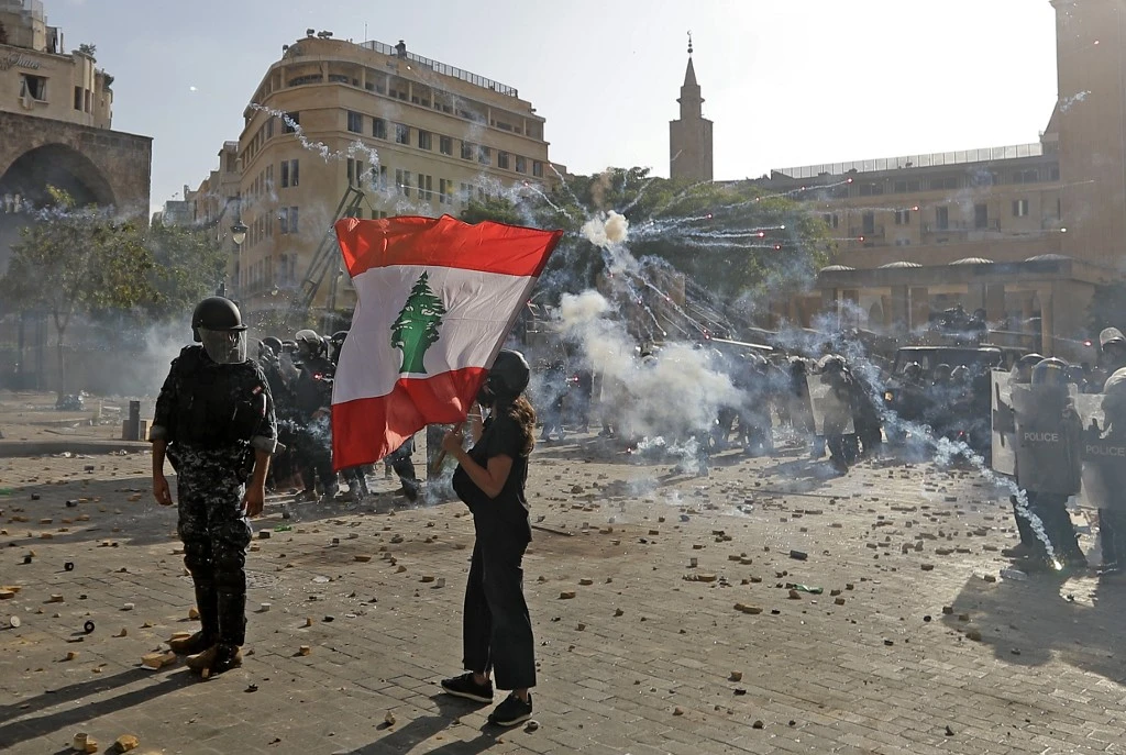 A Lebanese protester waves the national flag during clashes with security forces in downtown Beirut on August 8, 2020. (AFP)