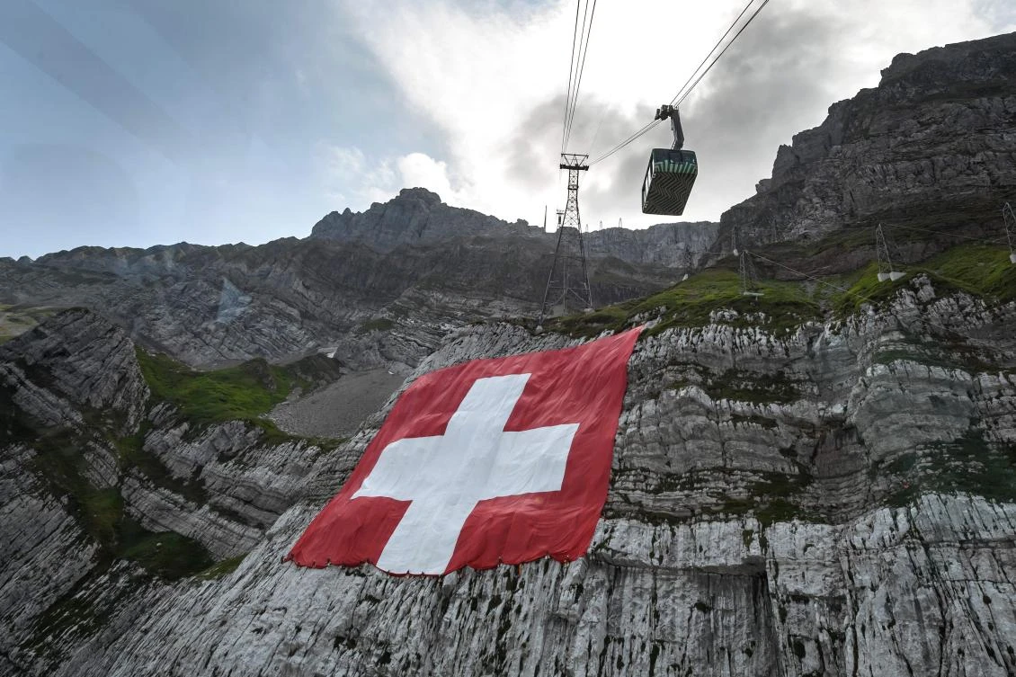 Climbers hang, on the rock face of mountain Saentis, a huge 6400 meters square Swiss flag on eve of Swiss national day on July 31, 2020 near Schwägalp, eastern Switzerland. Many Swiss stay in their country for holidays due to travel restriction due to the COVID-19 pandemic. (AFP)