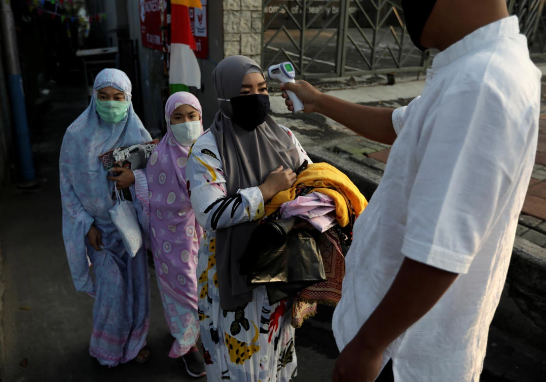 Temperature readings are taken for people attending Eid Al-Adha prayers in Jakarta during the outbreak of the coronavirus disease (COVID-19) in Indonesia, July 31, 2020. (Reuters)