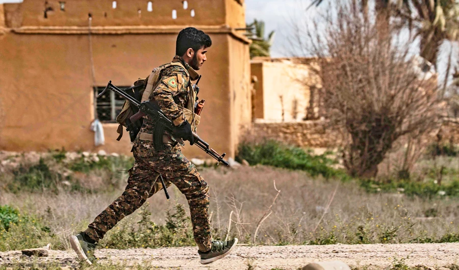 A member of the Syrian Democratic Forces (SDF) runs for cover during shelling on the Islamic State group's last holdout of Baghouz, in the eastern Syrian Deir Ezzor province on March 3, 2019. (AFP)