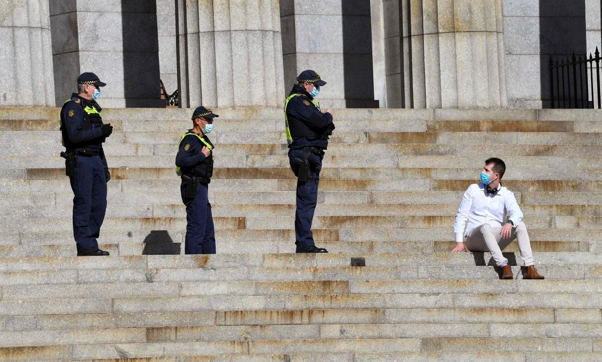 Protective Services officers speak to a man sitting on the steps of the Shrine of Remembrance in Melbourne on July 31, 2020. (AFP)