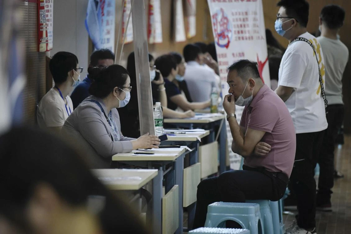 This photo taken on July 25, 2020 shows a job seeker (R) speaking with a recruiter of a company during a career fair in Zhengzhou, China's Henan province. China's economy may have rebounded sharply after a historic contraction from the coronavirus outbreak, but jobseekers face a less rosy situation -- with businesses still reeling and household savings on the rise. (AFP)