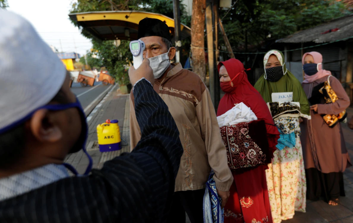 Temperature readings are taken for people attending Eid al-Adha prayers in Jakarta during the outbreak of the coronavirus disease (COVID-19) in Indonesia, July 31, 2020. (Reuters)