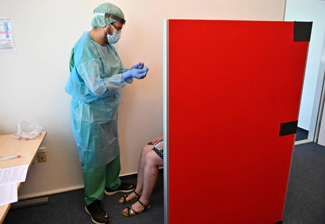 A health worker takes a swab sample from a client testing for the novel coronavirus COVID-19 at a test station at the Berlin-Schoenefeld airport in Berlin, on July 31, 2020. (AFP)